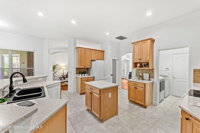 kitchen with arched walkways, a sink, decorative backsplash, white appliances, and a kitchen island