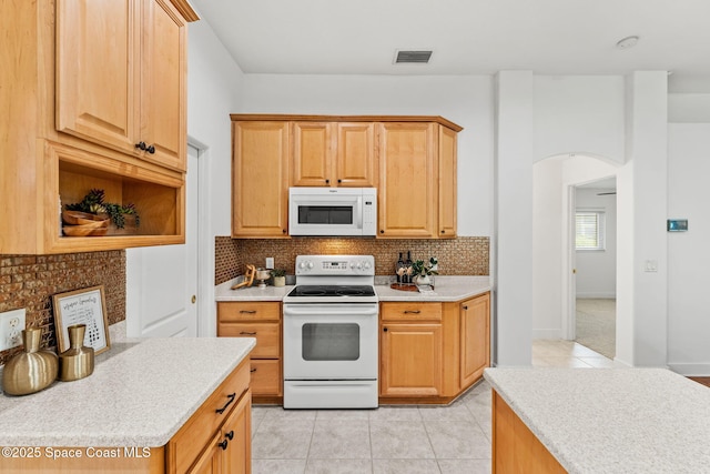 kitchen with backsplash, visible vents, light tile patterned floors, arched walkways, and white appliances
