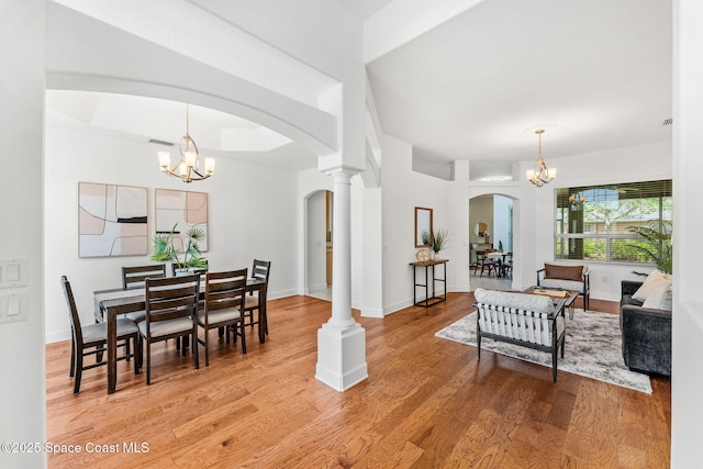 interior space with visible vents, arched walkways, light wood-style floors, baseboards, and a chandelier