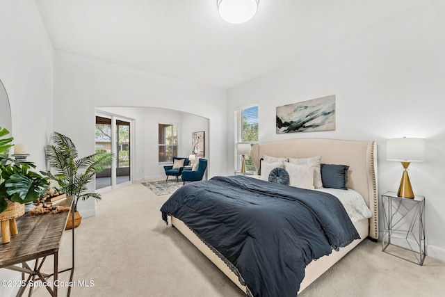 bedroom featuring arched walkways, carpet, access to exterior, and baseboards