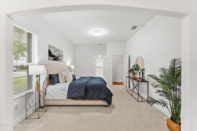 bedroom with arched walkways, carpet flooring, visible vents, and baseboards