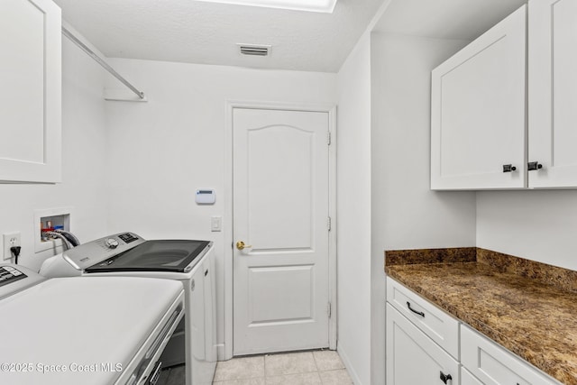 laundry room featuring washing machine and dryer, visible vents, cabinet space, and light tile patterned floors