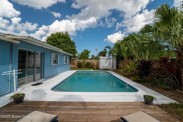 view of pool featuring a storage shed, a fenced backyard, an outdoor structure, a wooden deck, and a fenced in pool