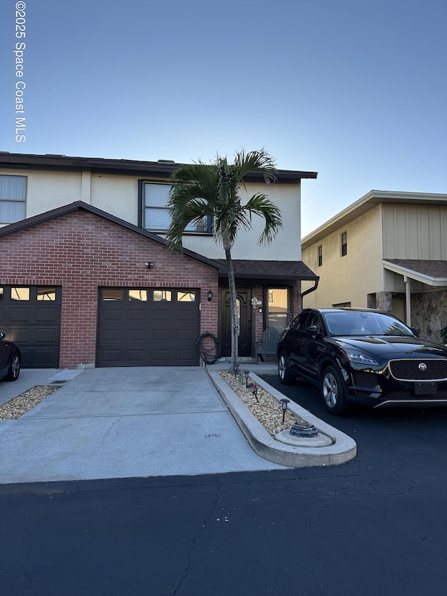 view of front facade with concrete driveway, brick siding, and stucco siding