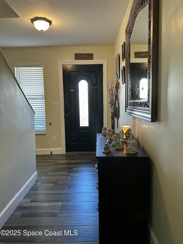 entrance foyer featuring dark wood-style flooring, a textured ceiling, and baseboards