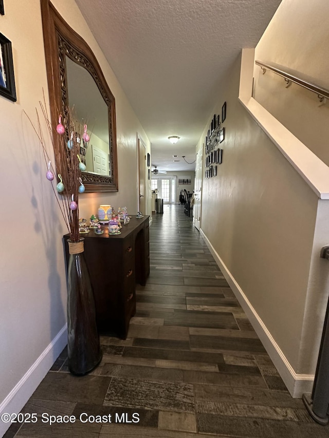 hall featuring dark wood-type flooring, a textured ceiling, and baseboards