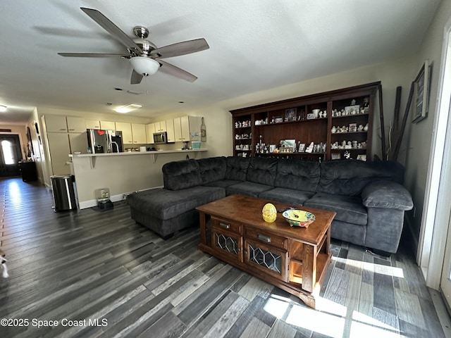 living area with a ceiling fan and dark wood-style floors