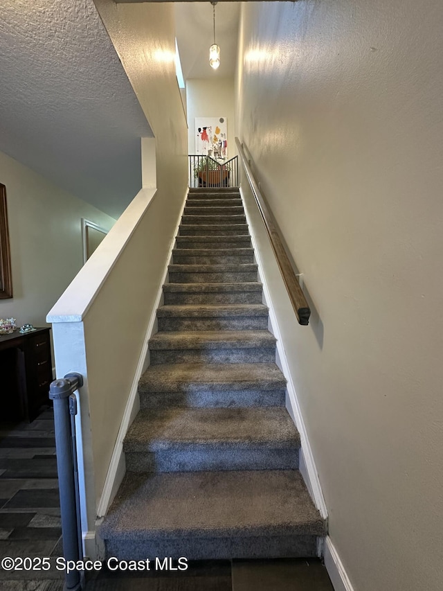 stairs with a textured ceiling and baseboards