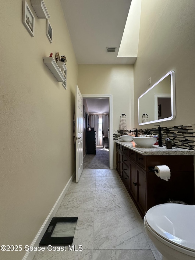 bathroom featuring visible vents, baseboards, marble finish floor, and vanity