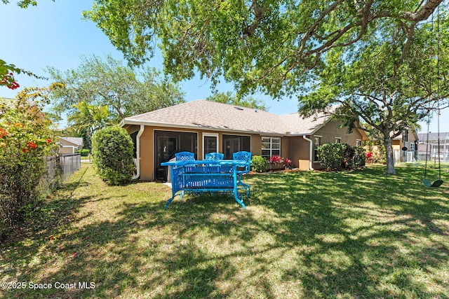 back of property featuring roof with shingles, stucco siding, fence, and a lawn