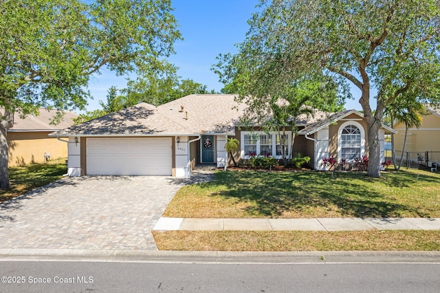 ranch-style home featuring a front yard, an attached garage, decorative driveway, and stucco siding