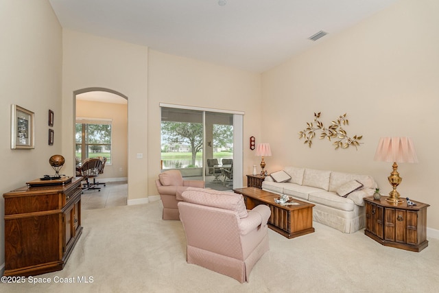 3156 Quint Dr, Melbourne, FL 32940 - living area featuring arched walkways, light carpet, baseboards, and a towering ceiling