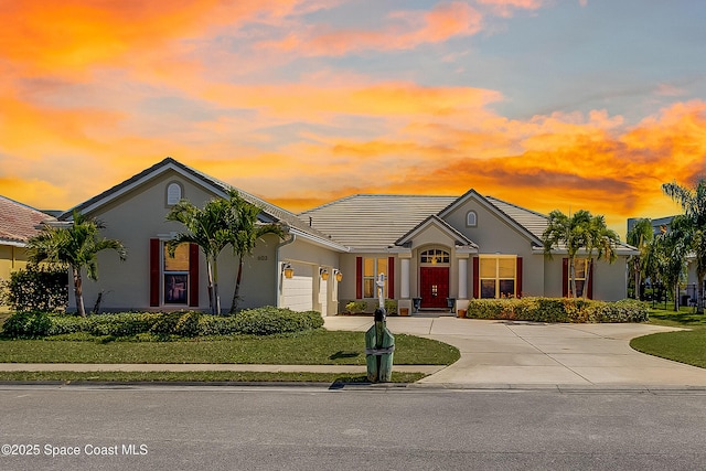 603 Manatee Bay Dr, Cape Canaveral, FL 32920 - view of front facade featuring curved driveway, an attached garage, stucco siding, a tile roof, and a front lawn