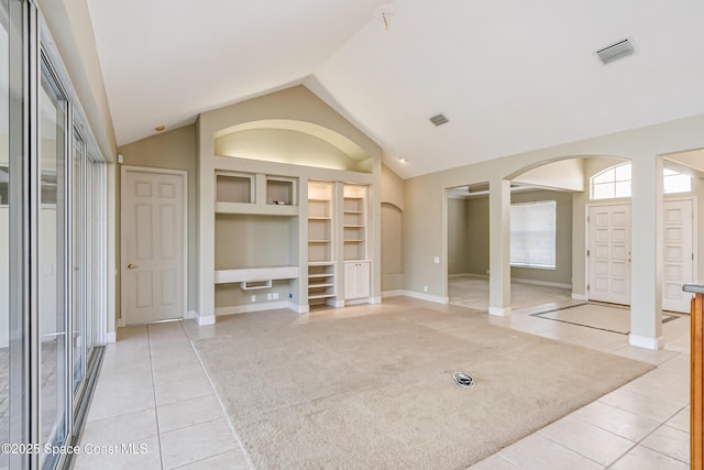 603 Manatee Bay Dr, Cape Canaveral, FL 32920 - unfurnished living room with light tile patterned floors, arched walkways, built in shelves, vaulted ceiling, and baseboards