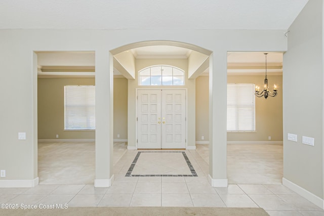 603 Manatee Bay Dr, Cape Canaveral, FL 32920 - foyer entrance with arched walkways, a chandelier, light tile patterned flooring, plenty of natural light, and ornamental molding