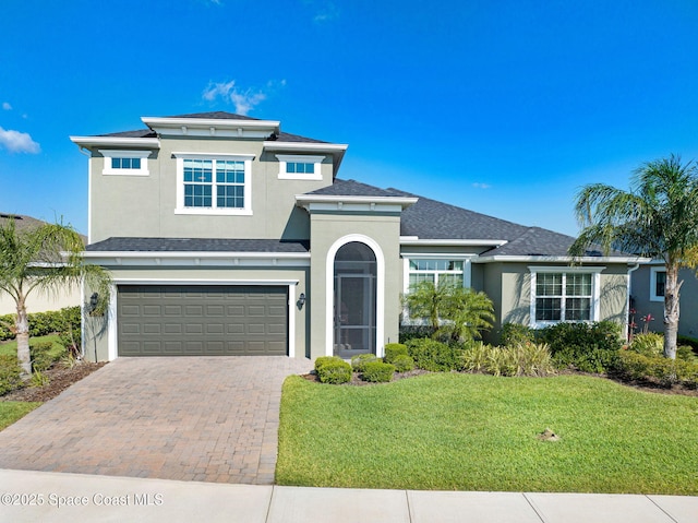 traditional home with a garage, a front yard, decorative driveway, and stucco siding