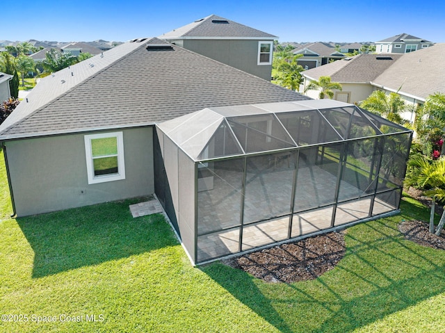 rear view of property featuring a shingled roof, a yard, a patio, stucco siding, and a residential view