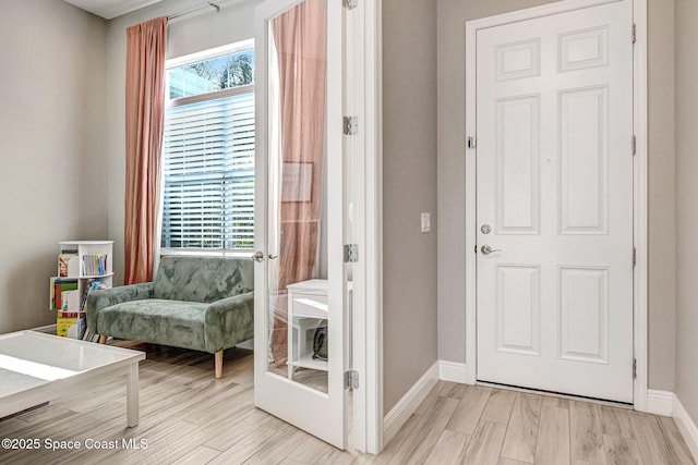 doorway to outside with light wood-style flooring, a healthy amount of sunlight, and baseboards