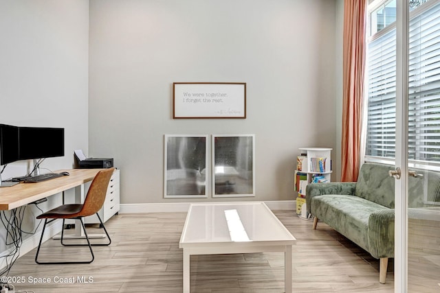 office area featuring light wood-type flooring, a wealth of natural light, and baseboards