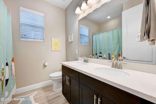 bathroom with wood finished floors, baseboards, a sink, and toilet
