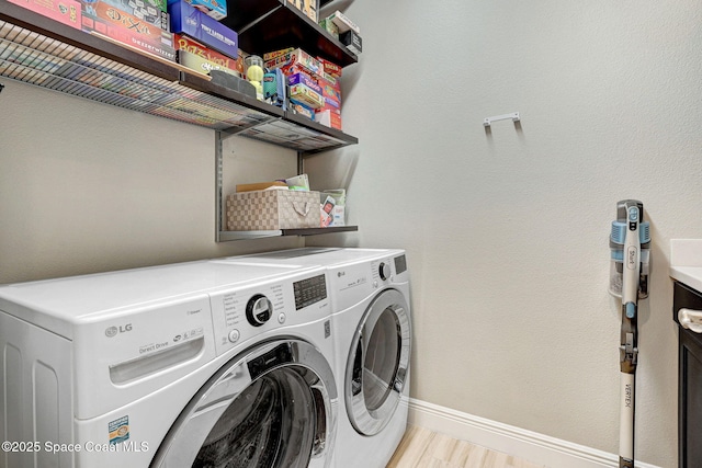 laundry room featuring washing machine and dryer, light wood finished floors, baseboards, and laundry area