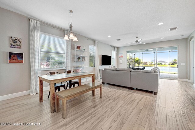dining room featuring baseboards, a ceiling fan, visible vents, and light wood-style flooring