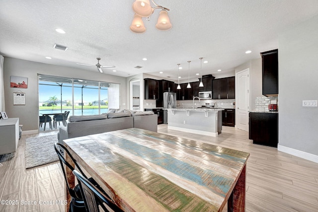 dining space with a ceiling fan, a textured ceiling, baseboards, visible vents, and recessed lighting