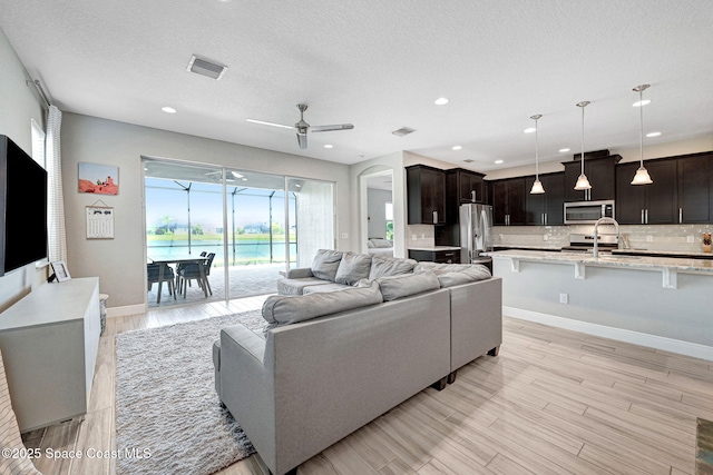 living room with light wood-type flooring, baseboards, a ceiling fan, and visible vents