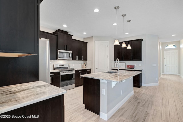 kitchen featuring tasteful backsplash, appliances with stainless steel finishes, baseboards, and a sink