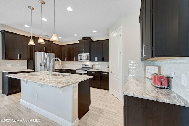 kitchen featuring decorative backsplash, stainless steel appliances, a sink, and light stone counters