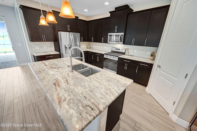 kitchen featuring light stone counters, appliances with stainless steel finishes, tasteful backsplash, and a sink