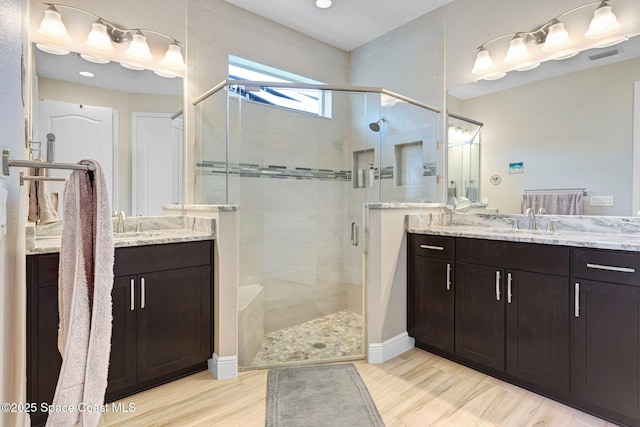 full bathroom featuring two vanities, a shower stall, and a sink