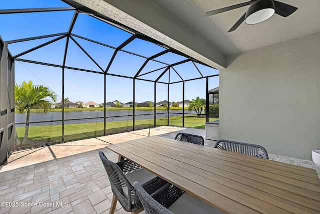 view of patio featuring a residential view, a water view, a lanai, ceiling fan, and outdoor dining space
