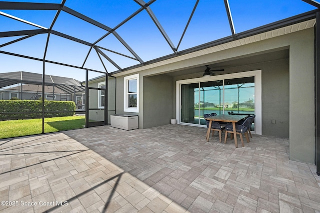 view of patio with a lanai, outdoor dining area, and ceiling fan