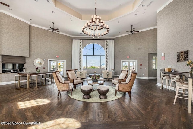 interior space with a high ceiling, a ceiling fan, ornamental molding, and a raised ceiling