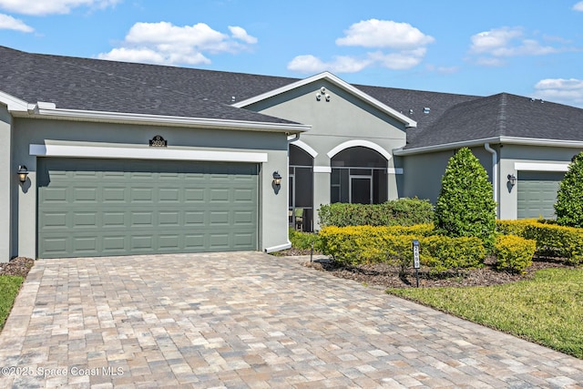 ranch-style home featuring roof with shingles, driveway, stucco siding, and an attached garage