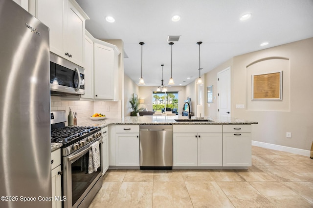 kitchen featuring appliances with stainless steel finishes, baseboards, a peninsula, decorative backsplash, and a sink