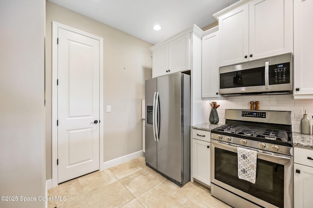 kitchen with baseboards, backsplash, white cabinets, light stone countertops, and appliances with stainless steel finishes
