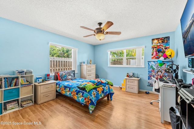 36 Mohican Way, Melbourne Beach, FL 32951 - bedroom featuring multiple windows, light wood-style floors, a textured ceiling, baseboards, and a ceiling fan
