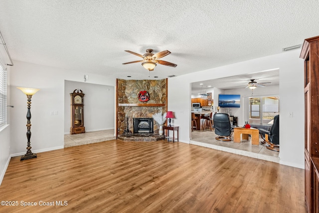 36 Mohican Way, Melbourne Beach, FL 32951 - living area with a ceiling fan, wood finished floors, a textured ceiling, and a stone fireplace