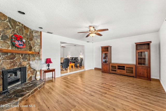 36 Mohican Way, Melbourne Beach, FL 32951 - living room featuring a ceiling fan, wood finished floors, a textured ceiling, baseboards, and a fireplace