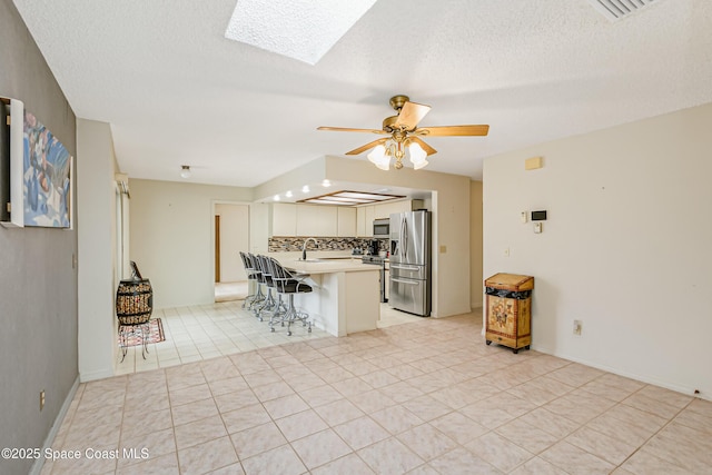 265 Sheridan Ave, Satellite Beach, FL 32937 - kitchen with a kitchen breakfast bar, ceiling fan, a skylight, appliances with stainless steel finishes, and light countertops