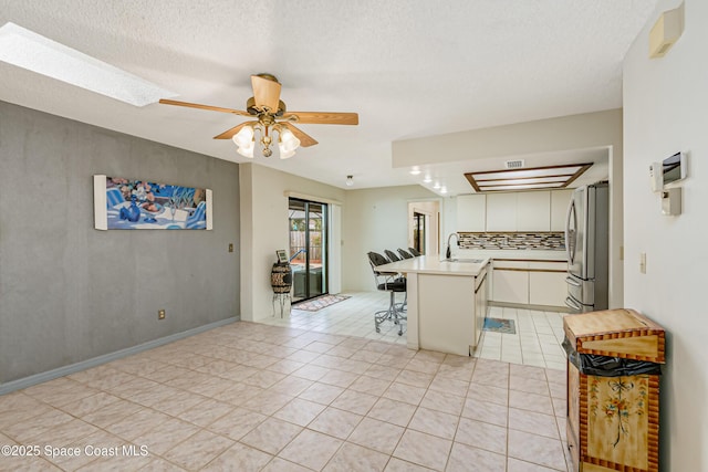 265 Sheridan Ave, Satellite Beach, FL 32937 - kitchen with a kitchen breakfast bar, ceiling fan, a sink, freestanding refrigerator, and white cabinetry