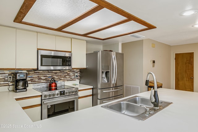 265 Sheridan Ave, Satellite Beach, FL 32937 - kitchen with appliances with stainless steel finishes, light countertops, cream cabinetry, backsplash, and visible vents