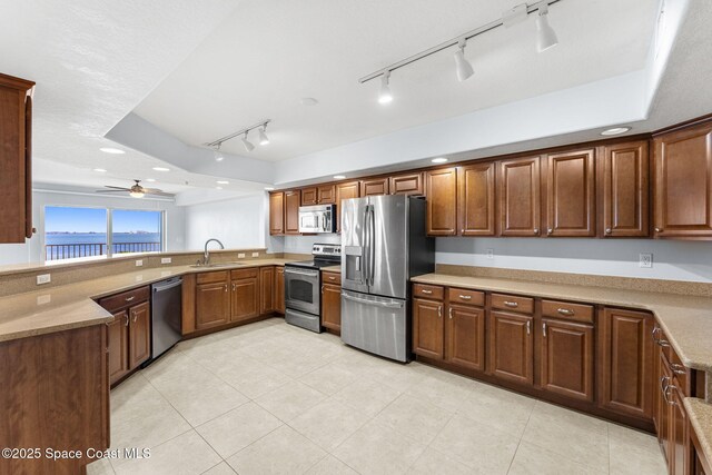 551 Casa Bella Dr Unit 501, Cape Canaveral, FL 32920 - kitchen featuring stainless steel appliances, a sink, rail lighting, a ceiling fan, and a peninsula