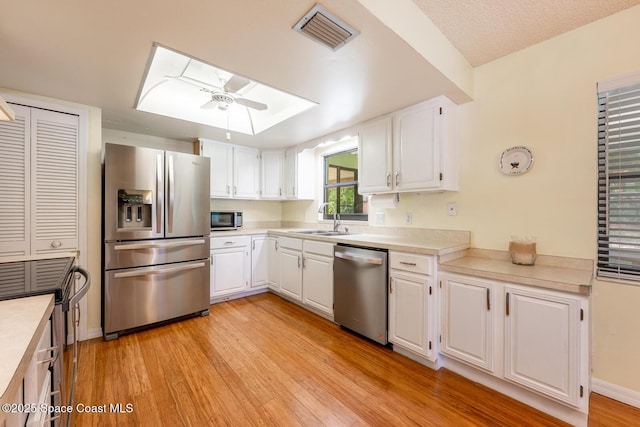 2102 E Parkton Dr, Deltona, FL 32725 - kitchen with a sink, stainless steel appliances, light wood-style floors, visible vents, and a skylight
