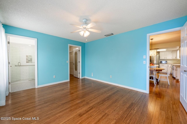 2102 E Parkton Dr, Deltona, FL 32725 - unfurnished bedroom with dark wood-style floors, stainless steel fridge, a walk in closet, visible vents, and a textured ceiling