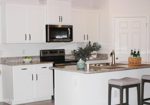 830 Remington Green Dr SE, Palm Bay, FL 32909 - kitchen featuring light stone countertops, a center island with sink, white cabinetry, a sink, and appliances with stainless steel finishes