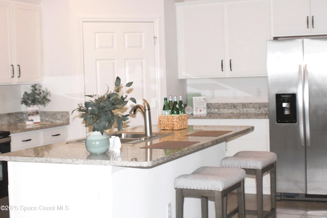 830 Remington Green Dr SE, Palm Bay, FL 32909 - kitchen featuring stainless steel fridge, white cabinetry, and a breakfast bar