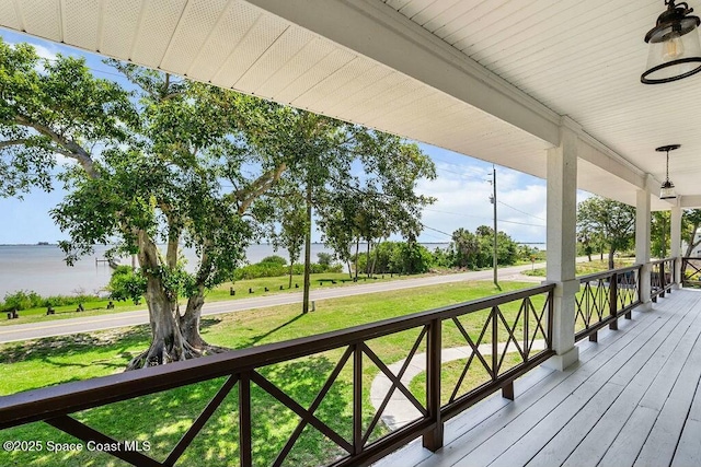 100 Woods S Dr, Merritt Island, FL 32952 - wooden deck featuring covered porch, a water view, a ceiling fan, and a lawn